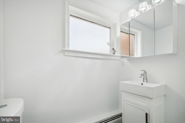 bathroom with toilet and vanity with extensive cabinet space