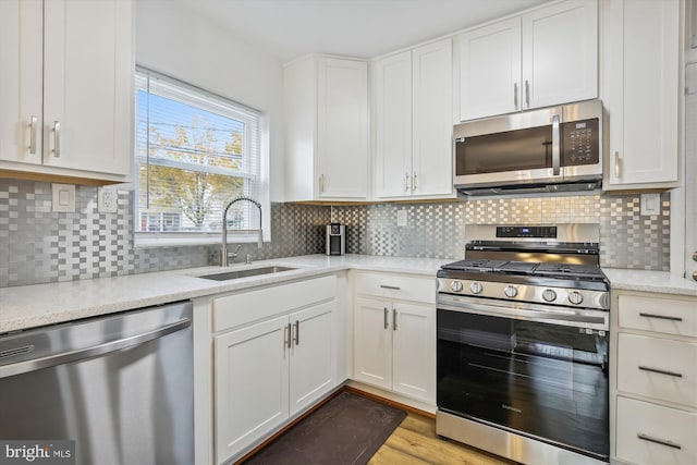 kitchen with white cabinetry, sink, tasteful backsplash, and stainless steel appliances