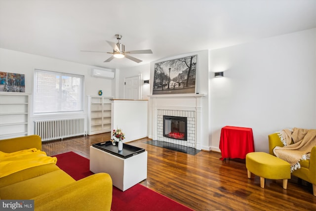 living room with a wall mounted AC, ceiling fan, radiator, a fireplace, and dark wood-type flooring