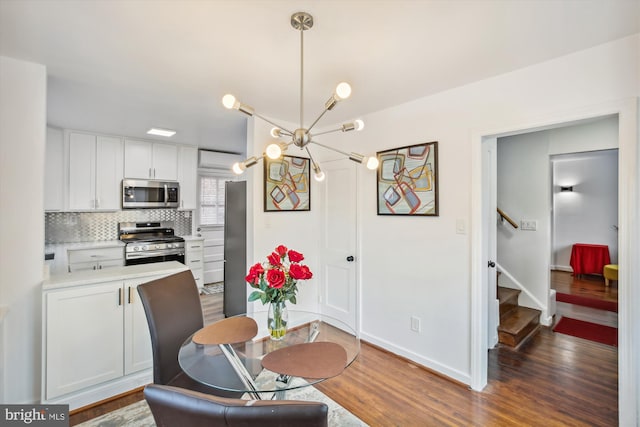 interior space with stainless steel appliances, white cabinets, a chandelier, tasteful backsplash, and dark hardwood / wood-style flooring