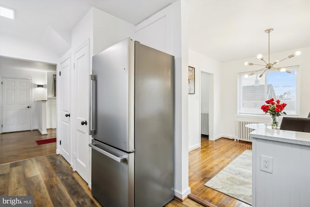 kitchen featuring stainless steel fridge, light stone countertops, a notable chandelier, and dark hardwood / wood-style floors