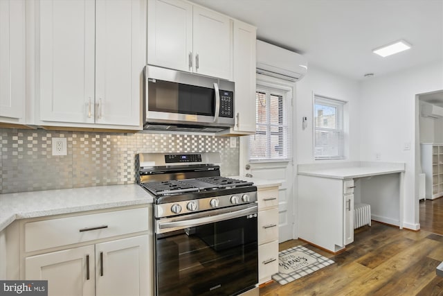 kitchen with white cabinetry, dark wood-type flooring, a wall unit AC, stainless steel appliances, and tasteful backsplash