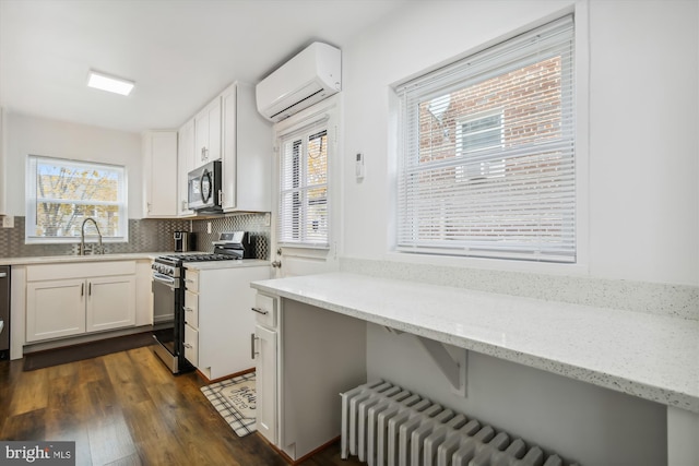 kitchen with white cabinetry, a wall mounted air conditioner, dark hardwood / wood-style floors, and stainless steel appliances