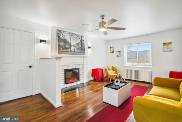 living room featuring a brick fireplace, ceiling fan, dark hardwood / wood-style floors, and radiator