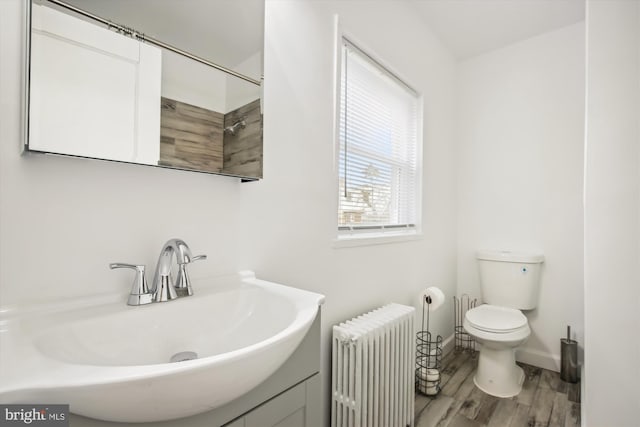 bathroom featuring toilet, vanity, radiator heating unit, and hardwood / wood-style flooring