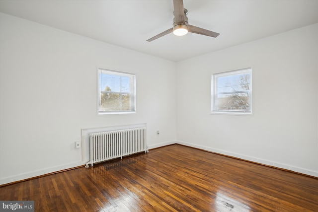 empty room with ceiling fan, dark hardwood / wood-style floors, radiator heating unit, and a healthy amount of sunlight