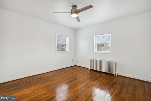 unfurnished room with plenty of natural light, dark hardwood / wood-style flooring, ceiling fan, and radiator heating unit