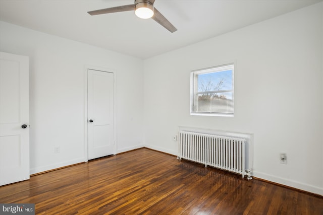 unfurnished room with ceiling fan, dark wood-type flooring, and radiator heating unit