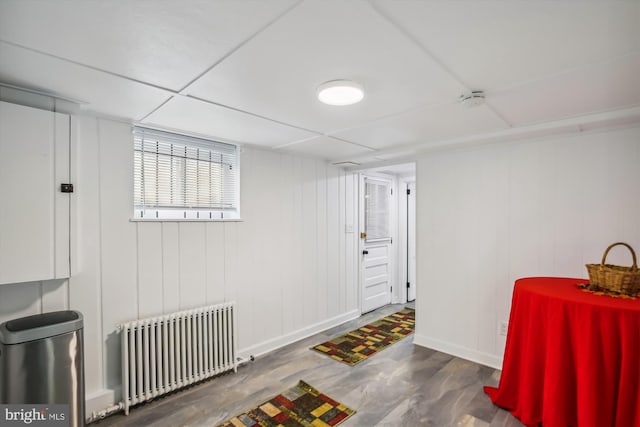 interior space with dark hardwood / wood-style floors, a paneled ceiling, and radiator