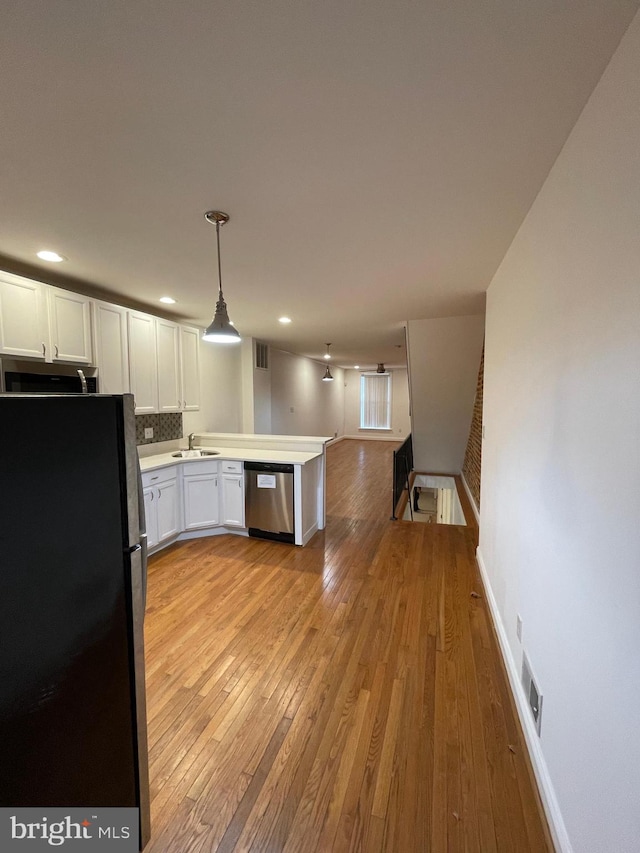 kitchen featuring decorative light fixtures, white cabinetry, light hardwood / wood-style floors, and black refrigerator