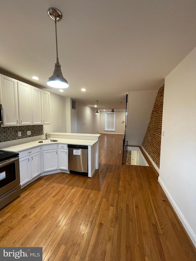 kitchen with appliances with stainless steel finishes, white cabinetry, light wood-type flooring, pendant lighting, and sink