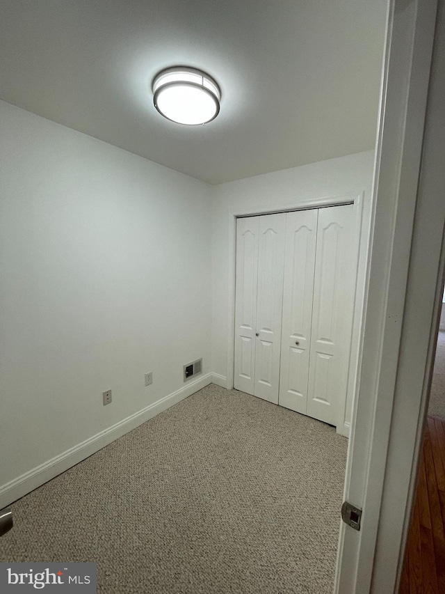 unfurnished bedroom featuring light carpet and a closet