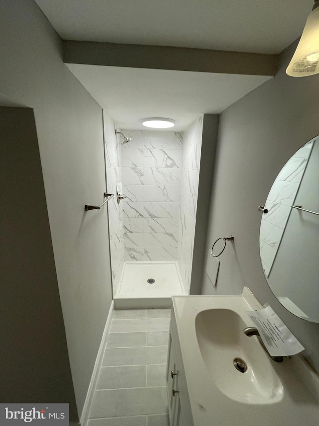 bathroom with tile flooring, tiled shower, and vanity