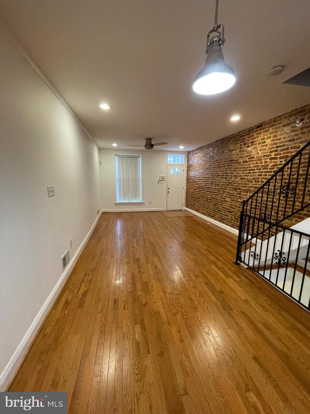 unfurnished room with brick wall, ceiling fan, and hardwood / wood-style flooring