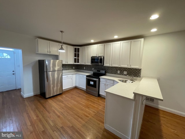 kitchen with dark hardwood / wood-style flooring, stainless steel appliances, white cabinets, and decorative light fixtures