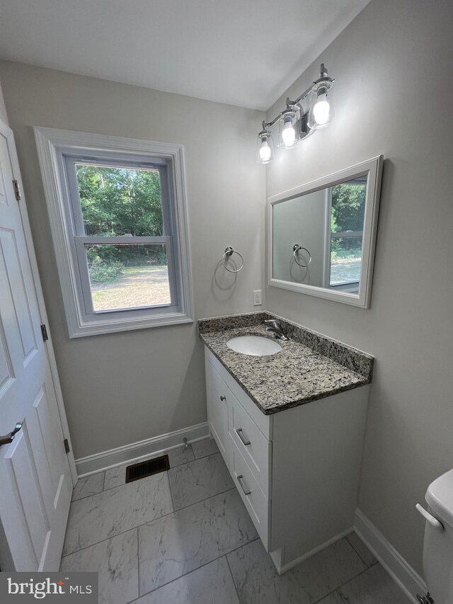 bathroom with tile flooring, large vanity, a healthy amount of sunlight, and toilet