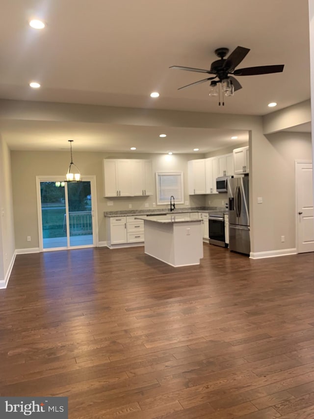 kitchen with stainless steel appliances, ceiling fan with notable chandelier, a center island with sink, and white cabinets