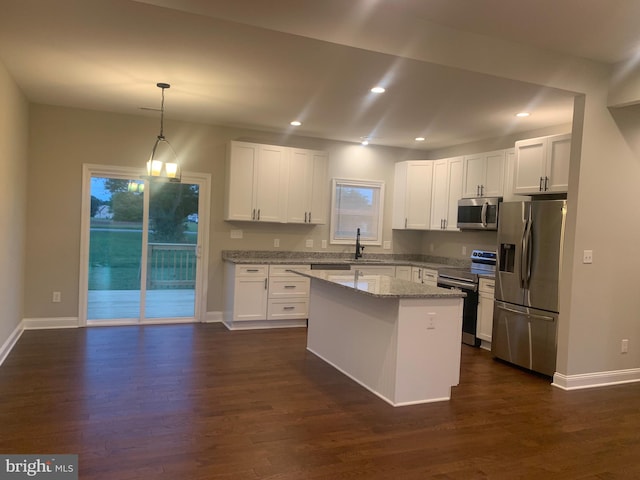 kitchen with appliances with stainless steel finishes, decorative light fixtures, light stone countertops, and dark hardwood / wood-style flooring