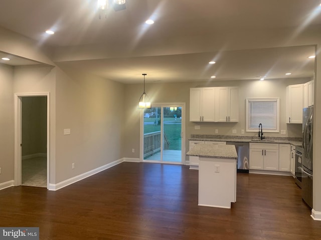 kitchen with pendant lighting, stainless steel appliances, a center island, dark hardwood / wood-style flooring, and light stone counters