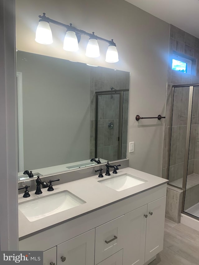 bathroom featuring a shower with shower door and dual bowl vanity