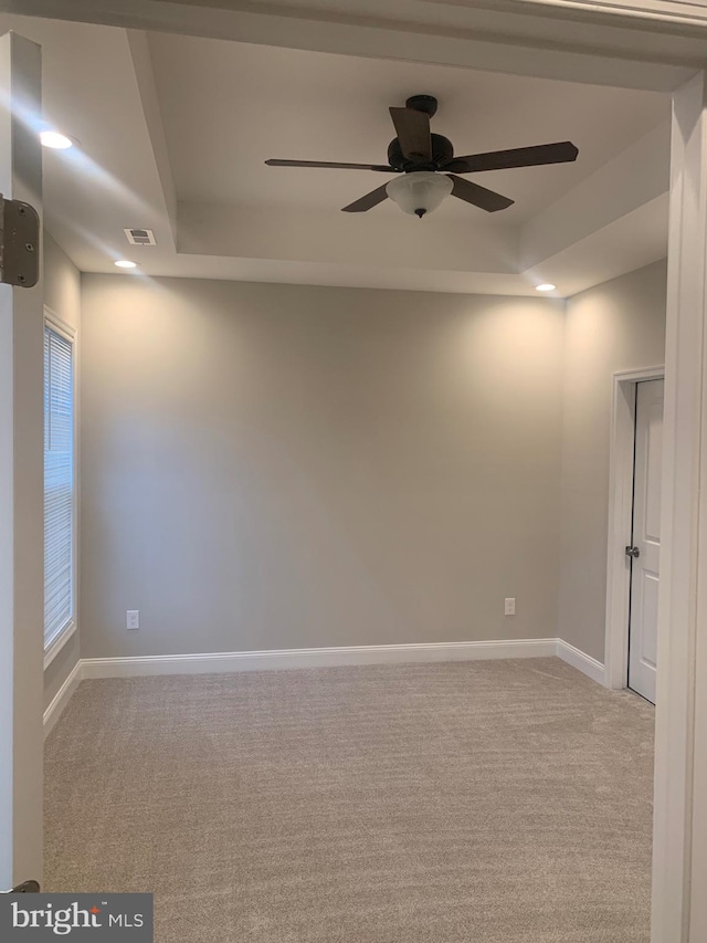 carpeted spare room featuring ceiling fan and a tray ceiling