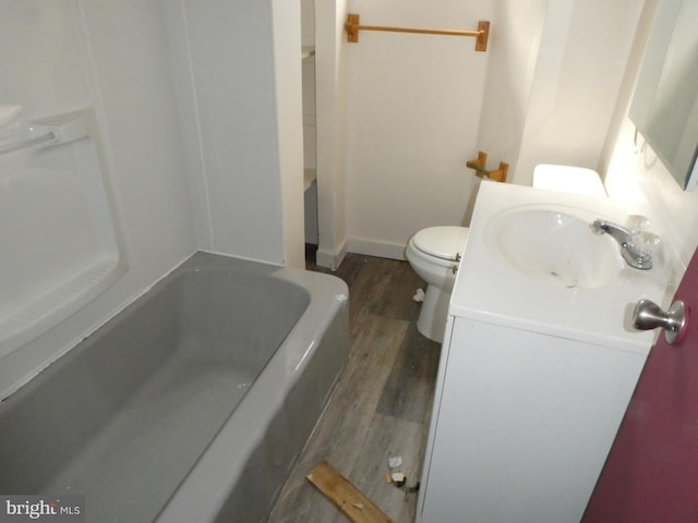 bathroom featuring wood-type flooring, vanity, toilet, and a bathing tub