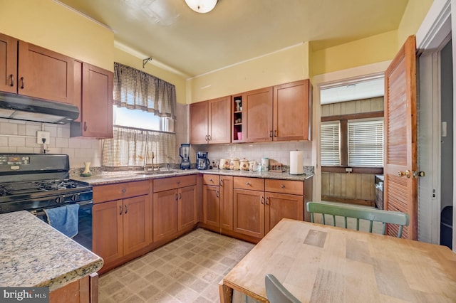 kitchen featuring sink, light tile floors, light stone counters, black gas range, and backsplash