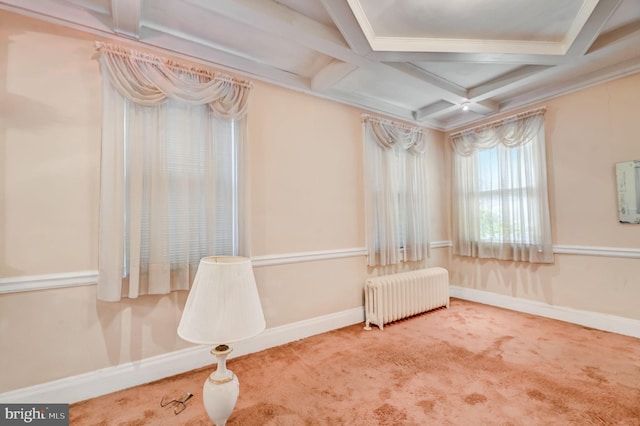 carpeted empty room featuring coffered ceiling, radiator heating unit, and beam ceiling