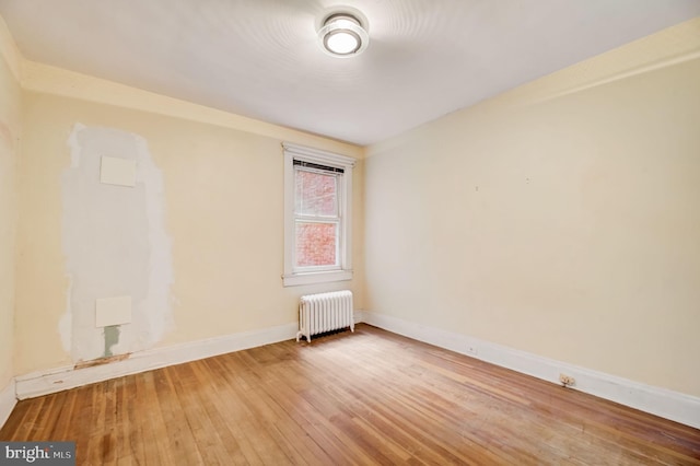 empty room featuring radiator heating unit and light wood-type flooring