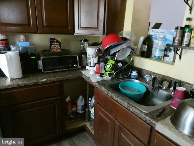 kitchen with dark brown cabinets, dark stone countertops, and sink