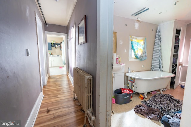 bathroom with radiator, a bathing tub, and hardwood / wood-style floors