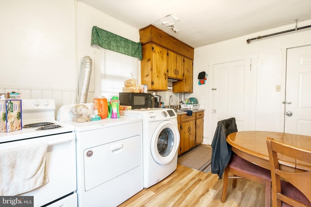 washroom with washing machine and clothes dryer, sink, and light wood-type flooring