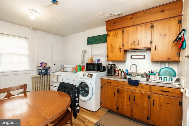 kitchen featuring radiator, white electric stove, sink, light hardwood / wood-style flooring, and washer / clothes dryer