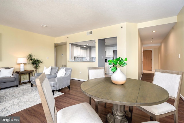 dining room with a textured ceiling and hardwood / wood-style flooring