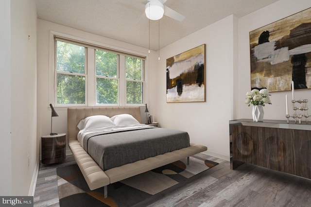 bedroom featuring ceiling fan, wood-type flooring, and a textured ceiling