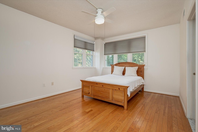 bedroom with ceiling fan, a textured ceiling, and light wood-type flooring