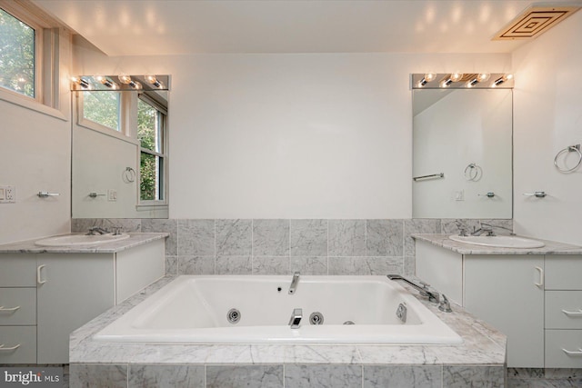 bathroom featuring vanity and a relaxing tiled tub