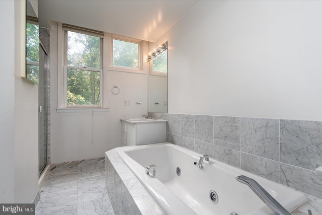 bathroom featuring vanity, vaulted ceiling, and tiled tub