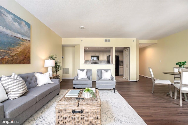 living room with a textured ceiling and dark wood-type flooring