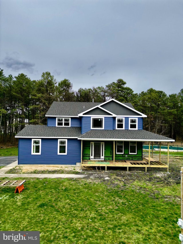 view of front of home featuring board and batten siding, covered porch, roof with shingles, and a front lawn