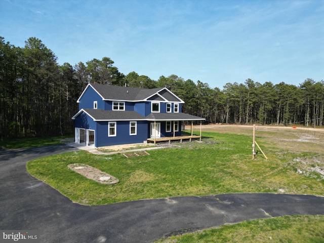 view of front of property featuring a garage, a porch, and a front lawn