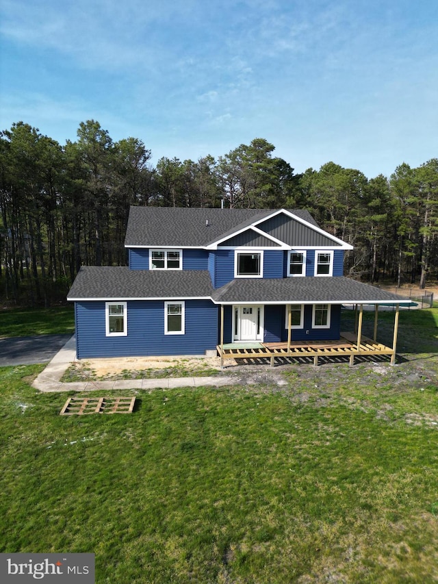 view of front of home with board and batten siding, a front yard, and a shingled roof