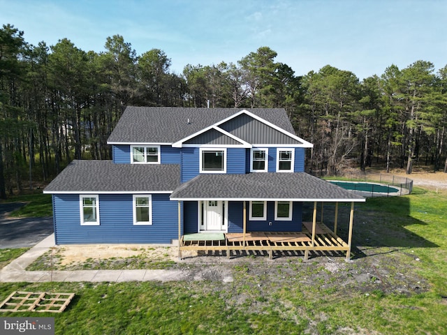 view of front facade featuring a porch, a front lawn, and a shingled roof