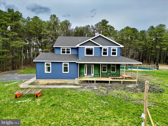 view of front facade featuring an outdoor pool, a porch, a front lawn, and a shingled roof