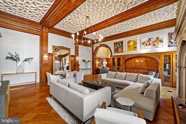 living room with dark parquet flooring, a towering ceiling, crown molding, and a chandelier