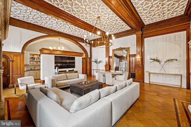 living room featuring parquet flooring, a towering ceiling, crown molding, sink, and an inviting chandelier