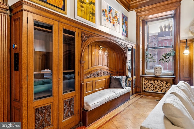 sitting room featuring wooden walls, light parquet floors, and ornamental molding