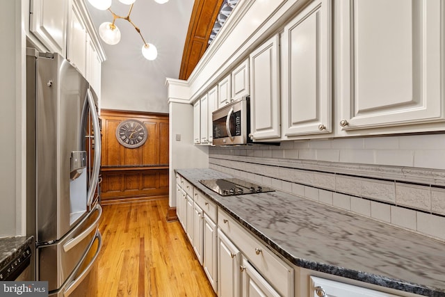 kitchen with backsplash, dark stone countertops, light hardwood / wood-style floors, white cabinetry, and stainless steel appliances