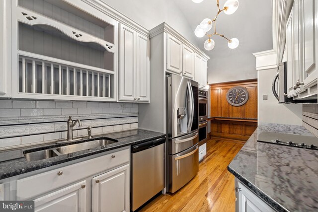 kitchen featuring appliances with stainless steel finishes, backsplash, sink, white cabinets, and light hardwood / wood-style floors