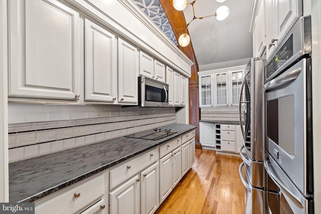 kitchen with stainless steel appliances, tasteful backsplash, light hardwood / wood-style flooring, dark stone counters, and white cabinets